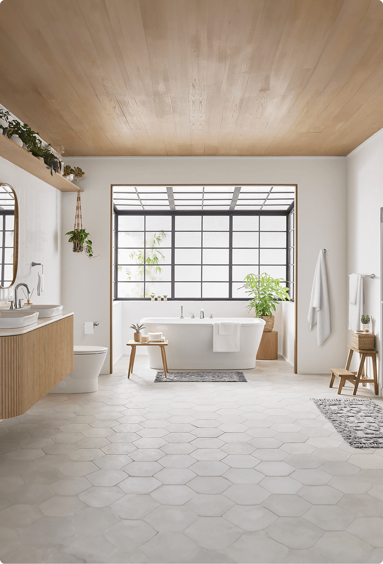 Bright bathroom with wood-paneled ceiling, freestanding soaking tub, dual vessel sinks, and hexagonal tile floor