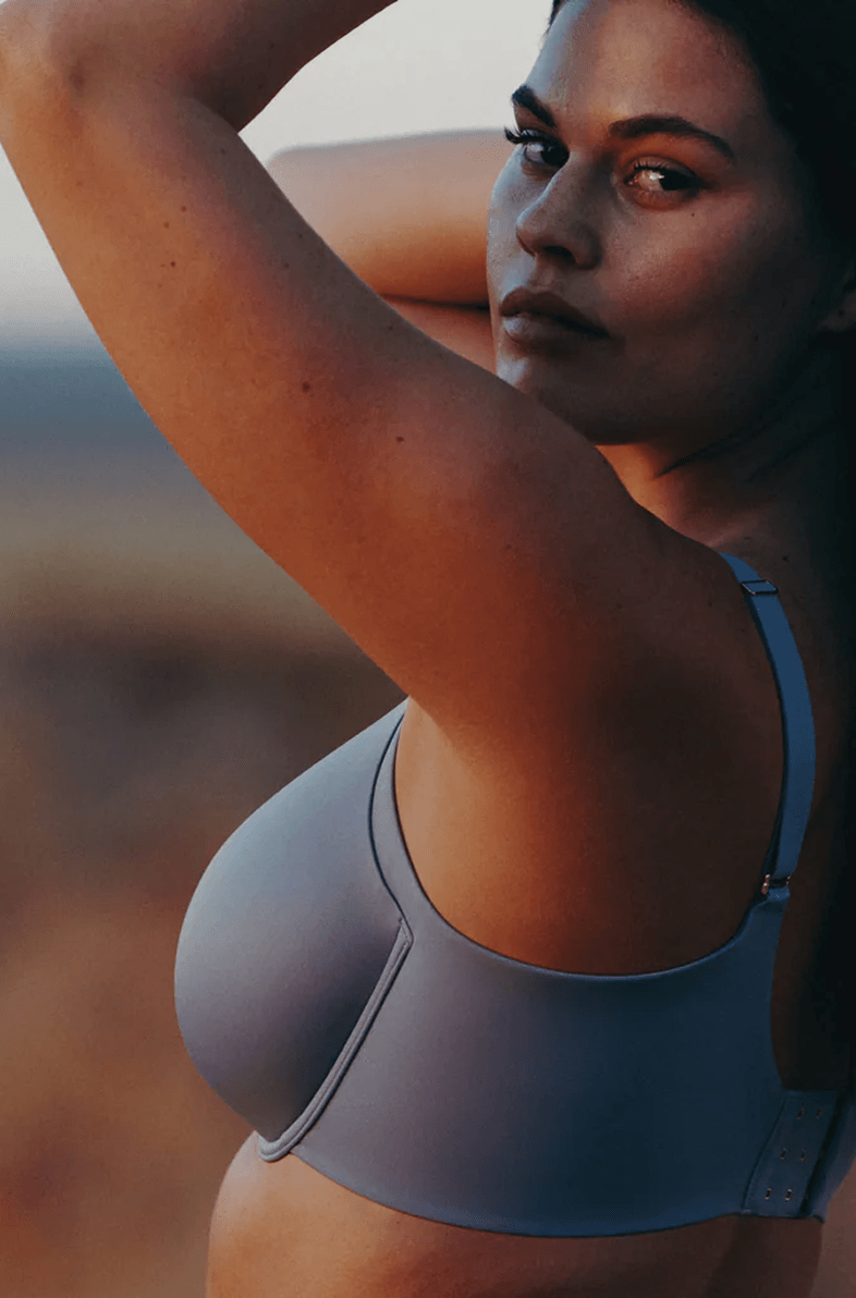 Contemporary home entryway at night with recessed lighting, a tall wooden pivot door, and a stone-paved walkway